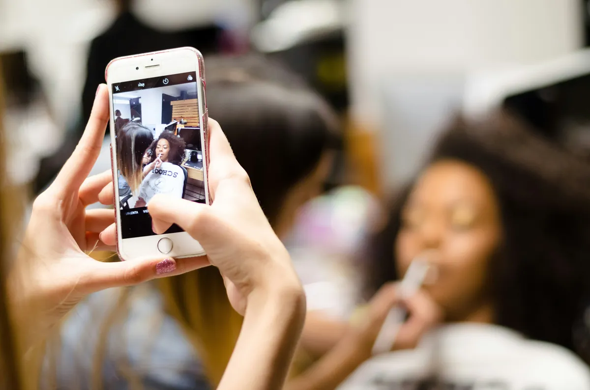 Beauty professional capturing portfolio work on a phone